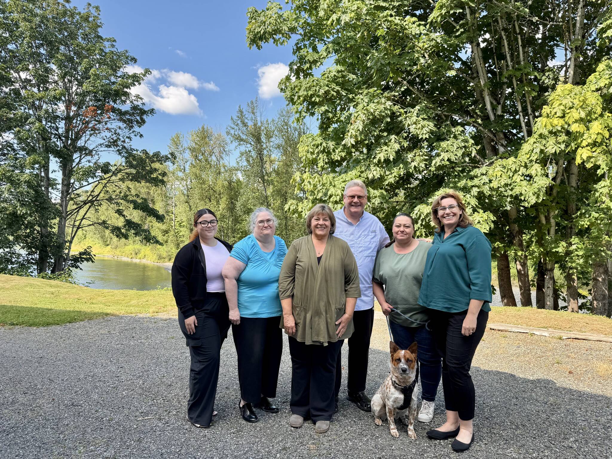 The staff of Hauglie Insurance, along with Copper the office dog, stands for a photo outside the agency by the Snoqualmie River, July 3, 2025. From left: Sophia Amaya Cruz, Elizabeth Gildersleeve, Laurie Hauglie, Kevin Hauglie, Samantha Darnell, Angela Donaldson. Grace Gorenflo/Valley Record