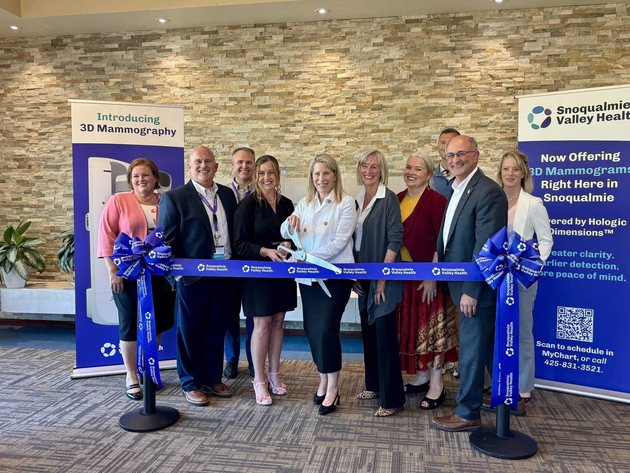 Snoqualmie Valley Health CEO Renée Jensen and radiologist Kara Carlson prepare to cut the ribbon at the opening of the hospitals mammography suite, July 22, 2025. From left: Chief Nursing Executive Tricia Ralston; imaging department manager Steve Bradshaw; CFO Patrick Ritter; Jensen; Carlson; North Bend Mayor Mary Miller; board member Jen Carter; Chief Medical Officer Jeremy Storm; Snoqualmie Councilmember Rob Wotton; chief of strategic operations Tammy Moore. Grace Gorenflo/Valley Record