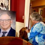In her Issaquah home, Sarah Perry and her dog, Sadie, sit with the photo of Bill Ramos used for his celebration of life, July 30, 2025. Perry said she keeps the photo in her home office so Ramos is always with her. (Grace Gorenflo/Valley Record)