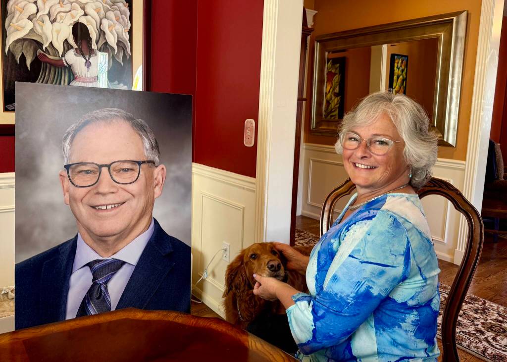 Sarah Perry and her dog, Sadie, sit with the photo of Bill Ramos used for his celebration of life in their Issaquah home, July 30, 2025. Perry said she keeps the photo in her home office so Ramos is always with her. (Grace Gorenflo/Valley Record)