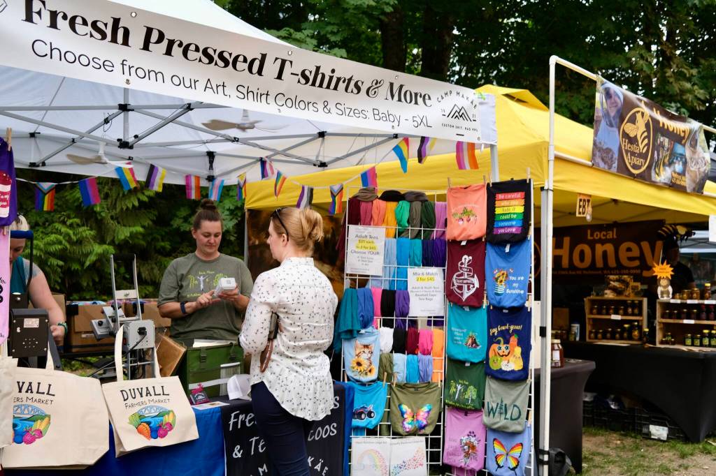 Fresh-pressed t-shirts and bags are for sale, including those with the Duvall Famers Market logo, at the market Sept. 4, 2025. (Grace Gorenflo/Valley Record)