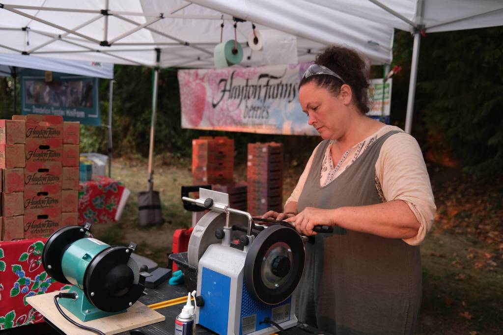 Vendor Erin Cox sharpens knives for customers at the Duvall Farmers Market, Sept. 4, 2025. (Grace Gorenflo/Valley Record)