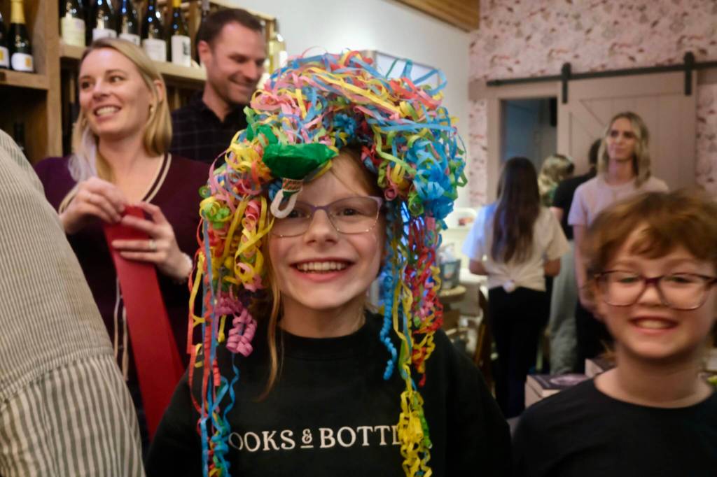 Owner Julie Thomass daughter celebrates the Books and Bottles ribbon cutting with streamers on her head, Nov. 14, 2025. Photos by Grace Gorenflo/Valley Record