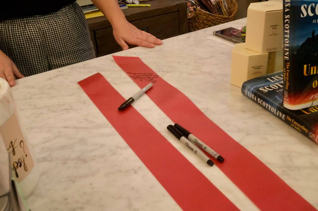 Guests sign the ribbon at the ribbon-cutting event of Books and Bottles, Nov. 14, 2025. (Grace Gorenflo/Valley Record)