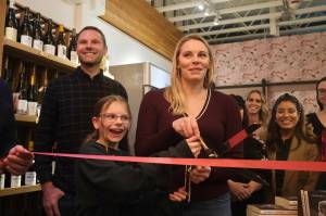 Books and Bottles owner Julie Thomas prepares to the cut the ribbon on her shop, joined by her husband and daughter, Nov. 14, 2025. (Grace Gorenflo/Valley Record)