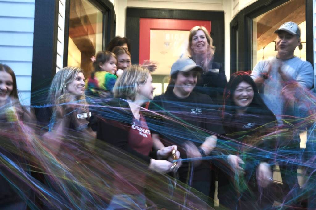 Falls Avenue Cookie Co. co-owners Heather Dean and Julie Chung, with their families, cut the ribbon at their grand opening, Nov. 19, 2025. (Grace Gorenflo/Valley Record)