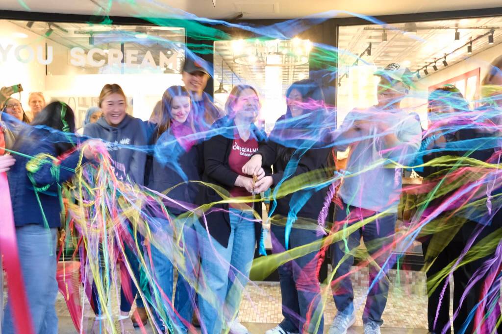 Snoqualmie Ice Cream co-owners Heather Dean and Julie Chung, with their families, cut the ribbon at their grand re-opening, Nov. 19, 2025. (Grace Gorenflo/Valley Record)