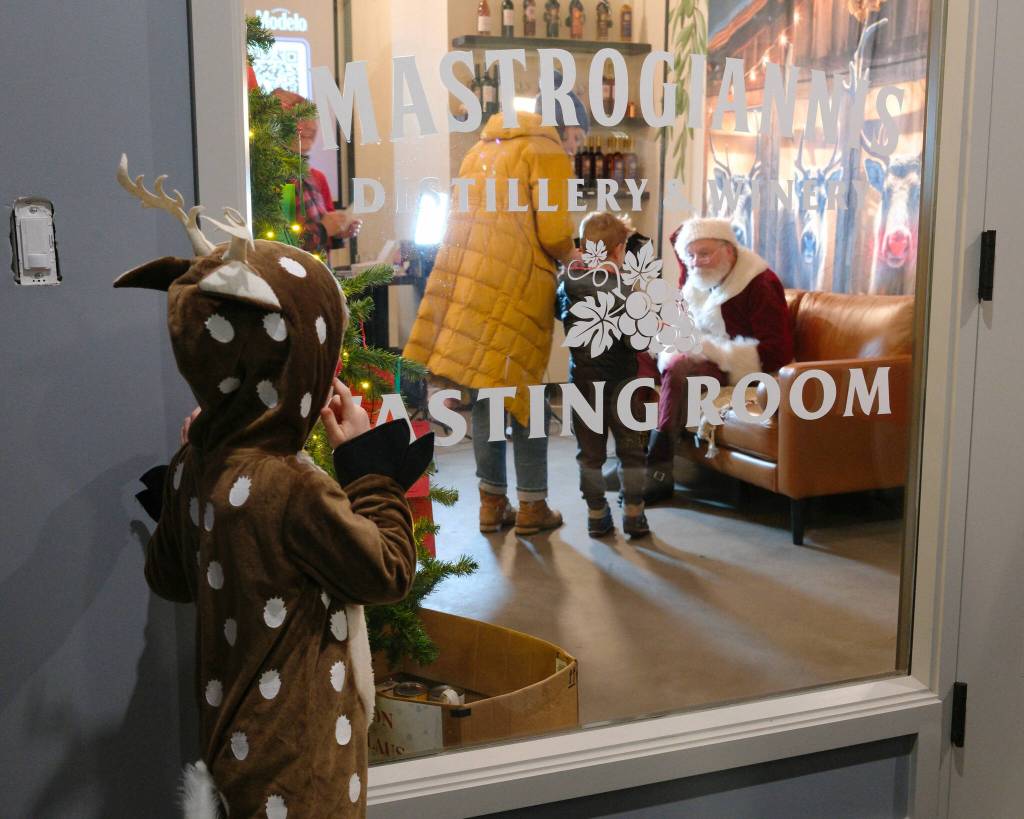 Costumed as a reindeer, Fritz Rode peers through a window at Mastrogiannis Distillery where kids and families queued up to meet Santa in North Bend on Saturday, Dec. 6.