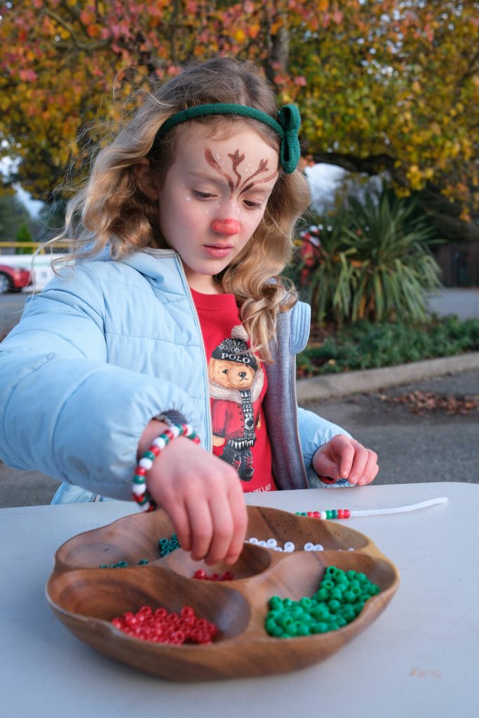 Stella, 7, makes a beaded bracelet at one of the many family-friendly tents set up by vendors, volunteers, and the Carnation Chamber. Despite a rainy forecast, the skies were mostly clear, save for chevrons of passing geese.