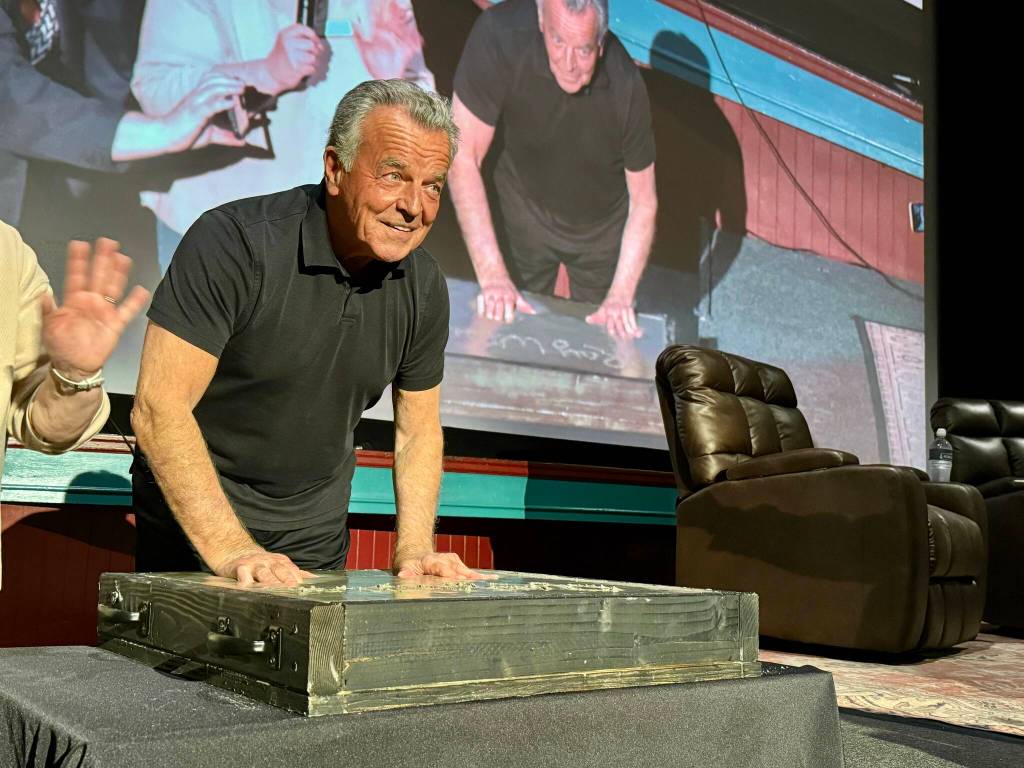 Actor Ray Wise, who played Leland Palmer in Twin Peaks, imprints his hands in a block of wet concrete at the North Bend Theatre, Feb. 22, 2025. The concrete block was added to the sidewalk outside the theater. (Grace Gorenflo/Valley Record)