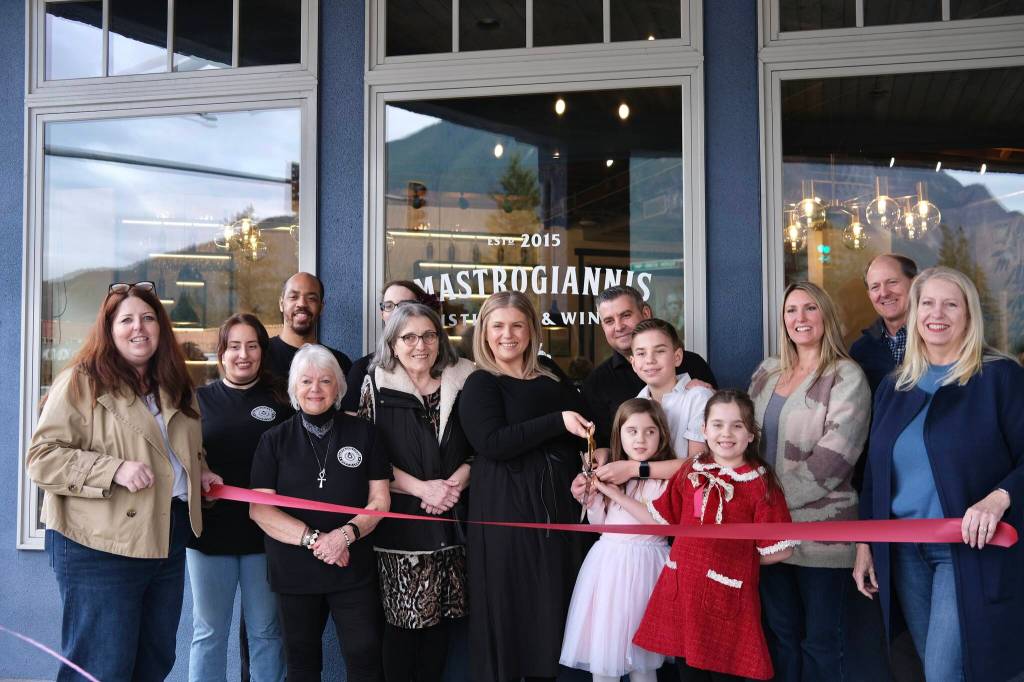 The Mastrogiannis family, surrounded by staff and local officials, prepares to cut the ribbon on their new North Bend distillery, March 5, 2026.