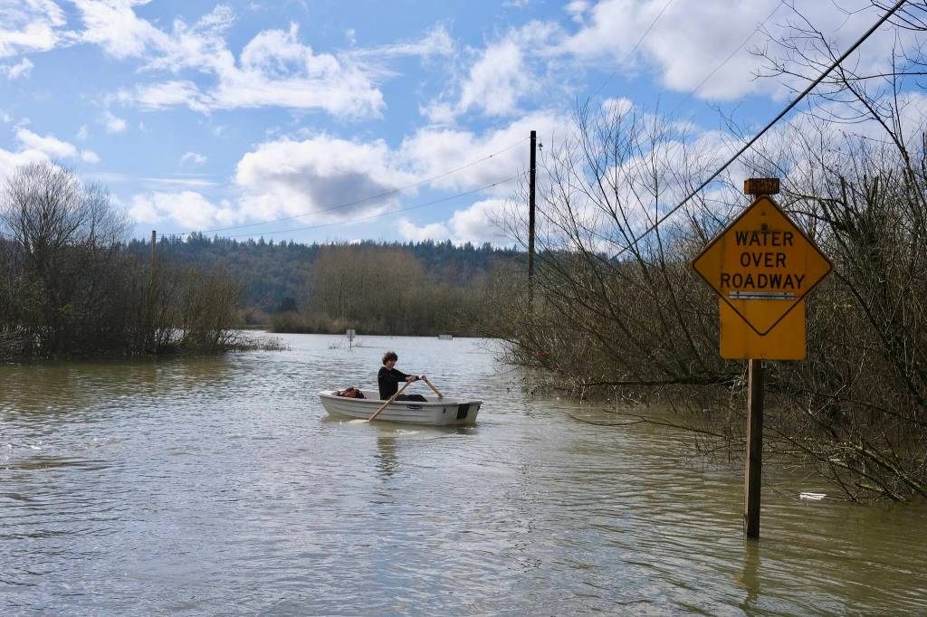 Felix Salvo, 15, rows his familys boat through flood waters on NE 124th Street, March 20, 2026. His parents own Local Roots Farm in Duvall. (Grace Gorenflo/Valley Record)