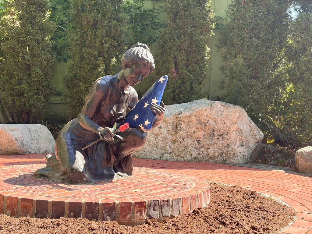 A statue depicting a woman with a rose and a folded American flag at the Snoqualmie Veterans Memorial. The statue, provided by Post 79, represents the spouses of fallen service members and is surrounded by names of the fallen. Photo by Faith Ellis