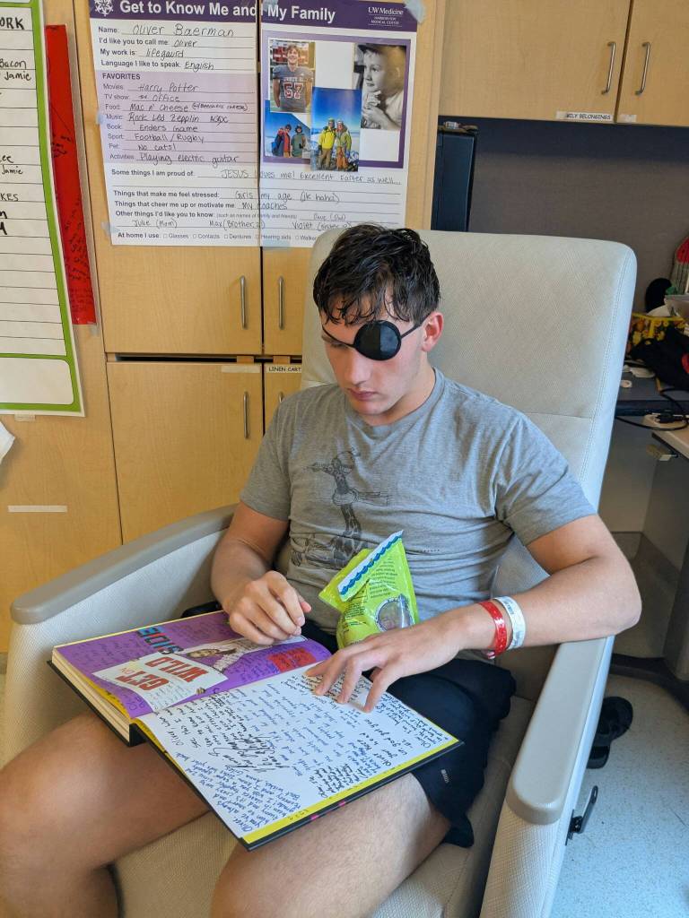 Oliver Baerman reads notes his peers wrote in his yearbook while still in the hospital in 2025. (Courtesy of Julie Baerman)